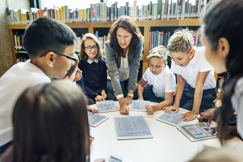 Leerkracht staat met tablet voor de klas