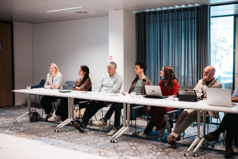 Groep mensen zit aan een vergadertafel tijdens een overleg